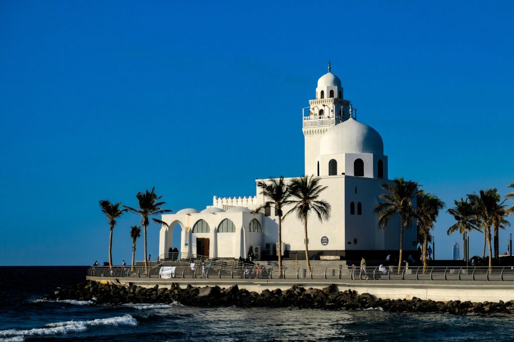 Scenic view of a beautiful mosque on a coastal promenade in Jeddah, Saudi Arabia against a clear blue sky.